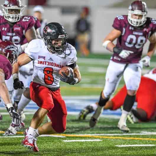 A student football player in possession of the ball during a game