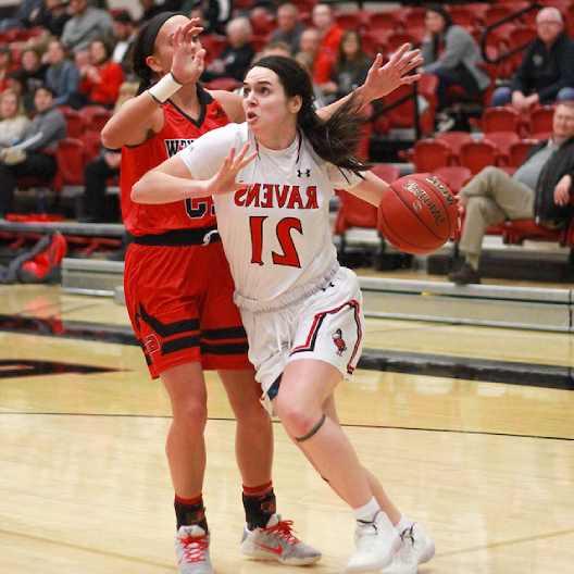 Lady Ravens basketball player pushing past a defender to score